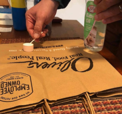 Putting out baby oil & Qtips on a paper bag on the kitchen table